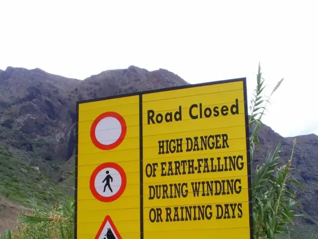 In this image we can see one sign board with some signs and some text on it. There are mountains,...